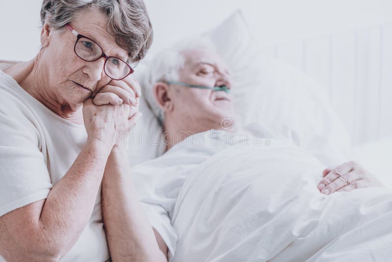 Sad elderly women taking care of her dying husband with alzheimer`s. Sad elderly women taking care of her dying husband with alzheimer`s