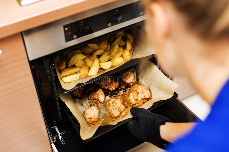 Donna che prepara le patate e carne di pollo in forno fotografia stock libera da diritti Donna che prepara le patate e carne di pollo in forno fotografia stock libera da diritti