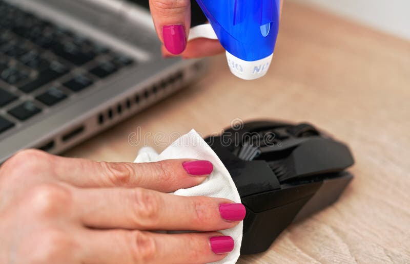 Donna che pulisce il mouse nero del computer che sta per disinfettare mentre lo tiene in mano con il tessuto di carta chiuso con l