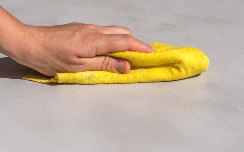 Donna che pulisce a mano l'acqua rovesciata su un pavimento di cemento con un panno di stoffa giallo per pavimenti fotografia stock