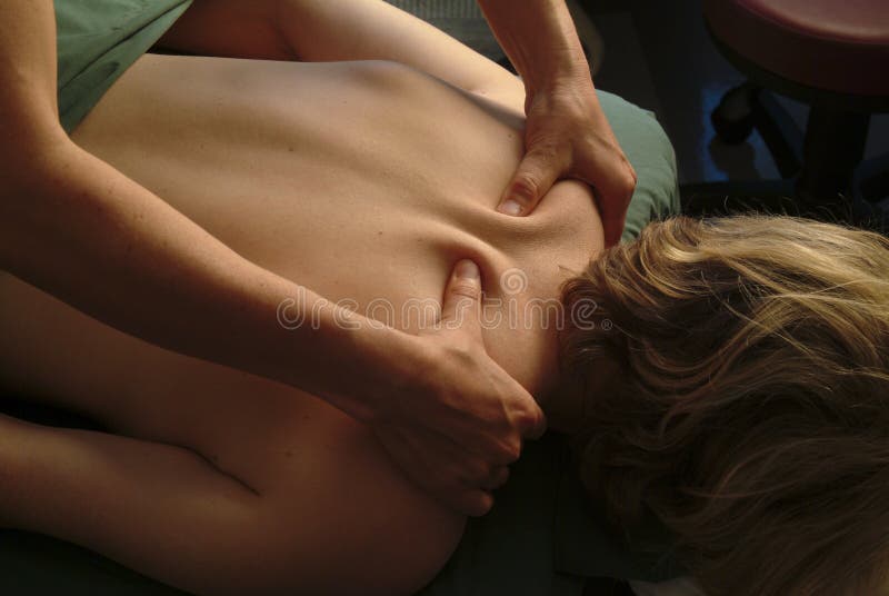 A young woman receives a back massage in a medical setting from a male masseuse. A young woman receives a back massage in a medical setting from a male masseuse.