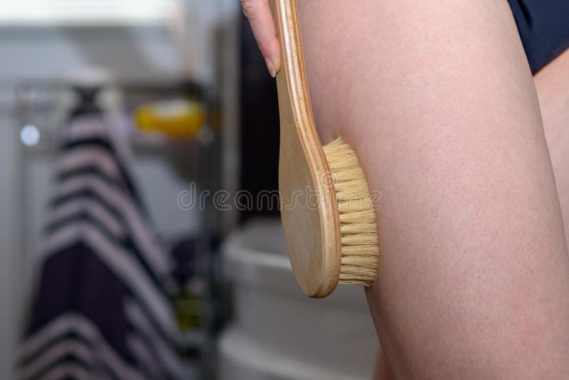 Donna che sfrega la sua coscia con una spazzola fotografie stock libere da diritti Donna che sfrega la sua coscia con una spazzola fotografie stock libere da diritti