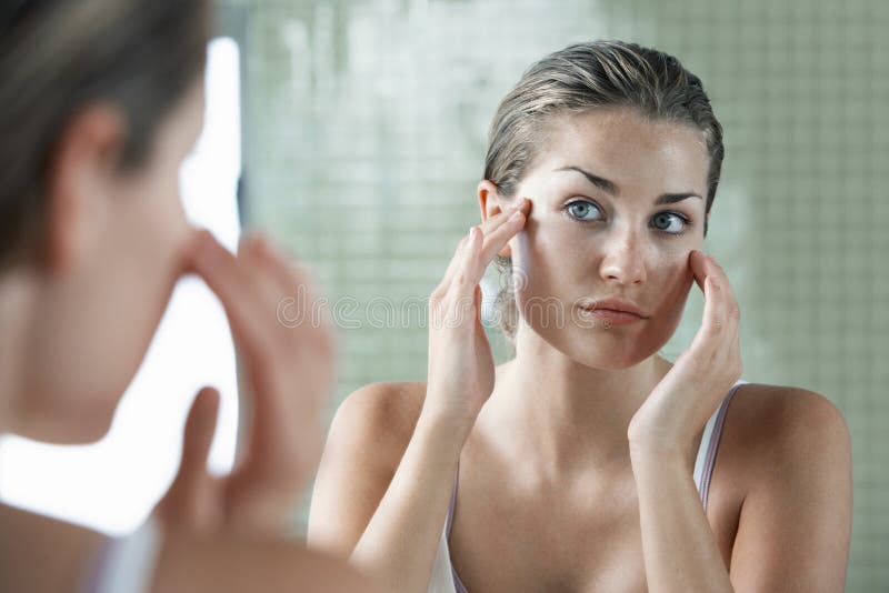 Donna che si esamina in Front Of Mirror immagine stock Donna che si esamina in Front Of Mirror immagine stock