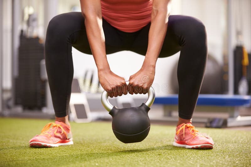 Donna che si esercita con un peso del kettlebell, il raccolto della basso sezione di vista frontale fotografie stock Donna che si esercita con un peso del kettlebell, il raccolto della basso sezione di vista frontale fotografie stock