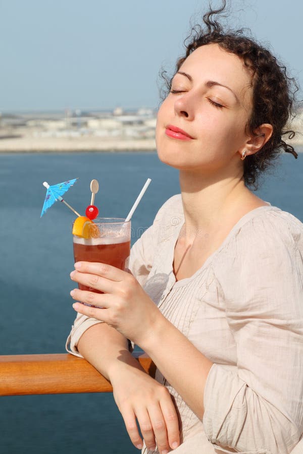Donna che si leva in piedi sulla fodera di crociera con il cocktail immagini stock Donna che si leva in piedi sulla fodera di crociera con il cocktail immagini stock