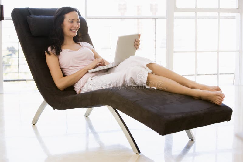 Donna che si siede nella presidenza per mezzo del computer portatile immagini stock Donna che si siede nella presidenza per mezzo del computer portatile immagini stock