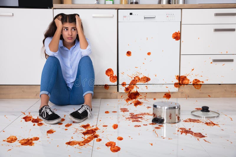 Unhappy Woman Sitting On Kitchen Floor With Spilled Food In Kitchen. Unhappy Woman Sitting On Kitchen Floor With Spilled Food In Kitchen