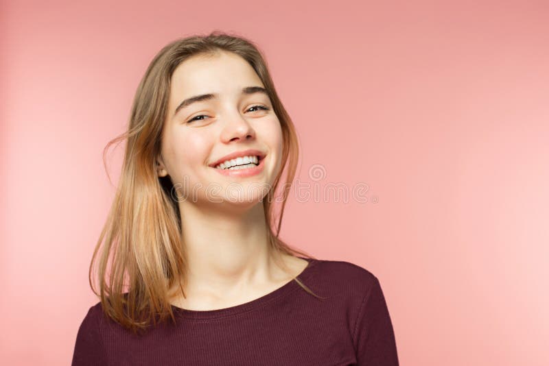 Donna che sorride con il sorriso perfetto ed i denti bianchi sui precedenti rosa dello studio e che esamina macchina fotografica fotografia stock