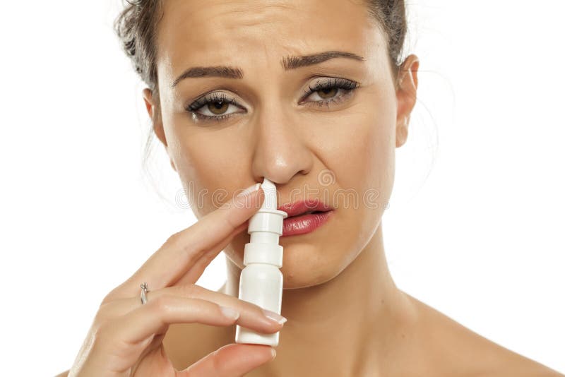 Young sad woman spraying nasal drops in her nose. Young sad woman spraying nasal drops in her nose