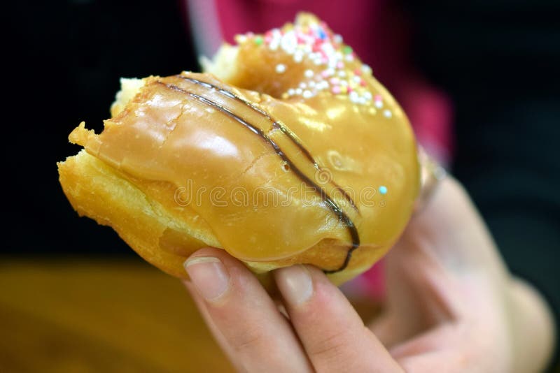 Donna che tiene una mezza ciambella alimentare immagine stock Donna che tiene una mezza ciambella alimentare immagine stock