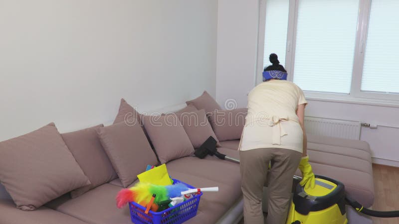 Una persona che usa un aspirapolvere per pulire un divano.