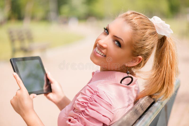 Donna che utilizza compressa digitale nel parco immagine stock