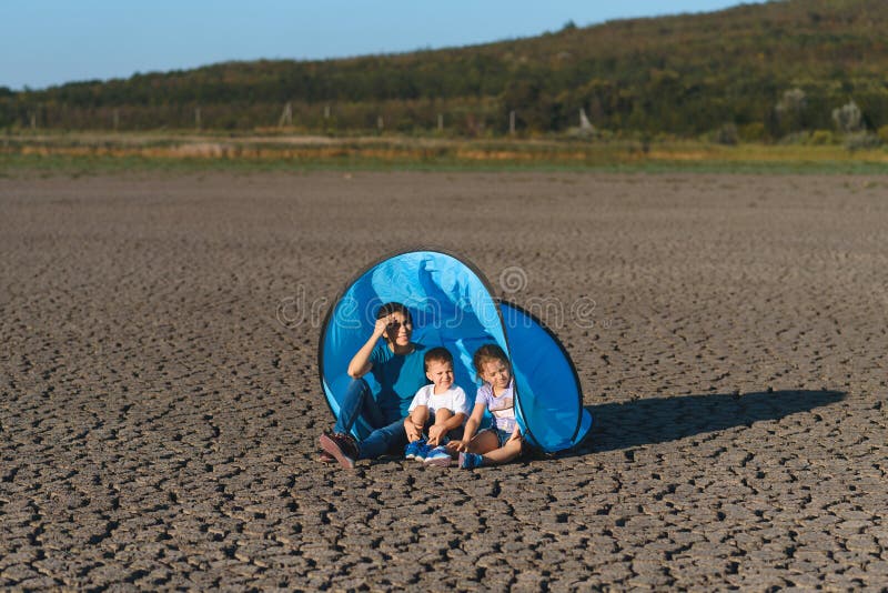 Donna con i bambini in tenda sul lago secco
