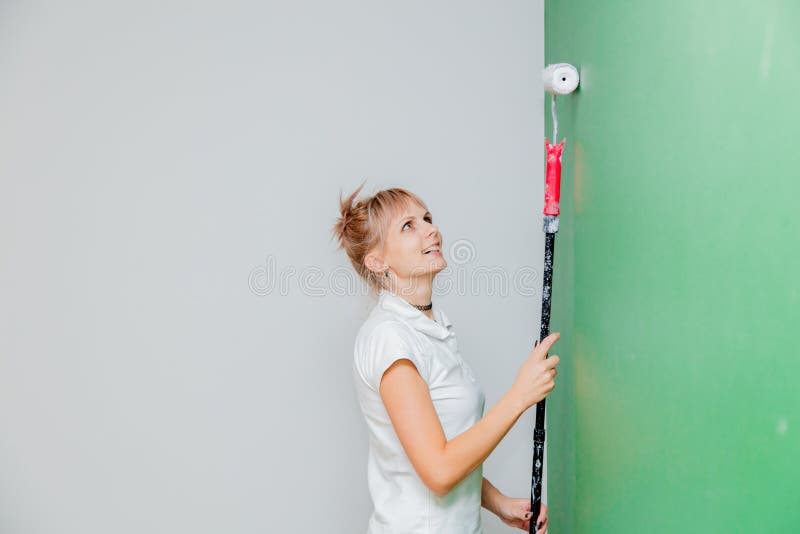 Donna con il rullo di pittura nella propria casa fotografia stock Donna con il rullo di pittura nella propria casa fotografia stock