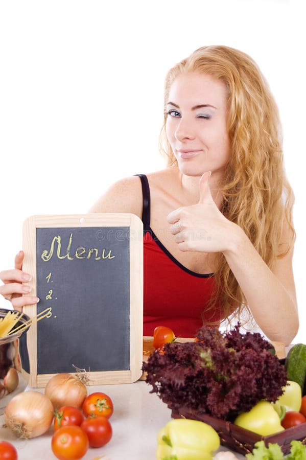 Woman winks with manu board, vegetables and thumb up over white. Woman winks with manu board, vegetables and thumb up over white