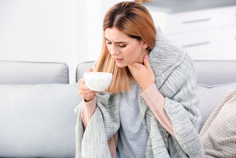 Donna con la tazza di tè per la tosse sul sofà