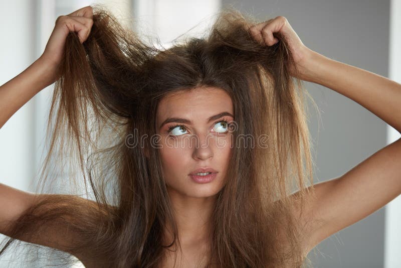 Donna con la tenuta dei capelli asciutti lungamente nocivi Danno dei capelli, Haircare fotografia stock libera da diritti Donna con la tenuta dei capelli asciutti lungamente nocivi Danno dei capelli, Haircare fotografia stock libera da diritti