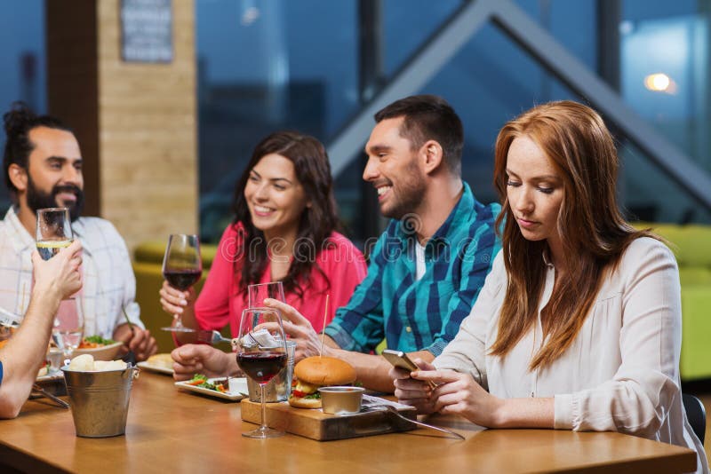 Donna con smartphone e amici al ristorante immagini stock libere da diritti