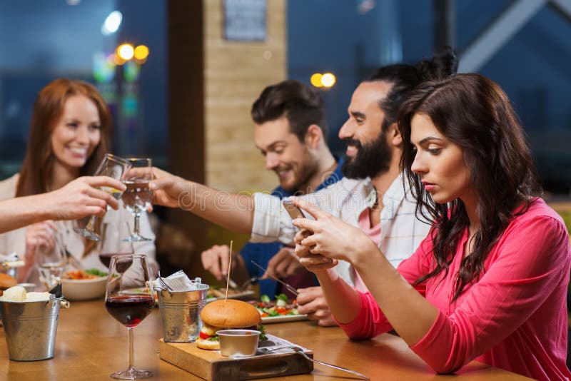 Donna con lo smartphone e gli amici al ristorante fotografia stock