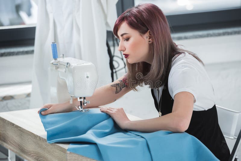 Donna concentrata che adatta i vestiti in officina fotografia stock libera da diritti Donna concentrata che adatta i vestiti in officina fotografia stock libera da diritti