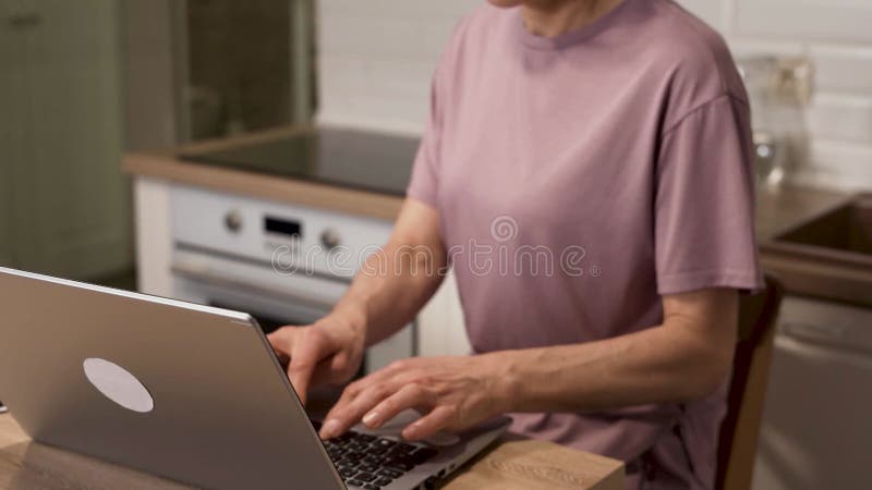 Donna concentrata che usa il computer portatile sul tavolo della cucina di casa video d archivio