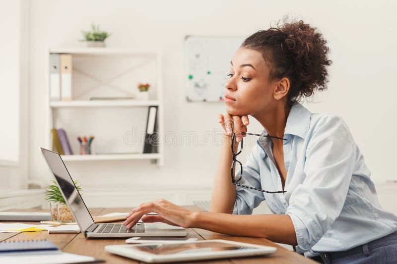 Donna concentrata di affari che lavora al computer portatile all'ufficio fotografie stock Donna concentrata di affari che lavora al computer portatile all'ufficio fotografie stock