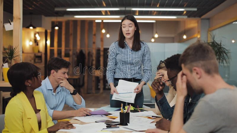 Donna d'affari arrabbiata che urla contro i colleghi durante l'incontro d'ufficio Giovani gruppi multirazziali che lavorano in