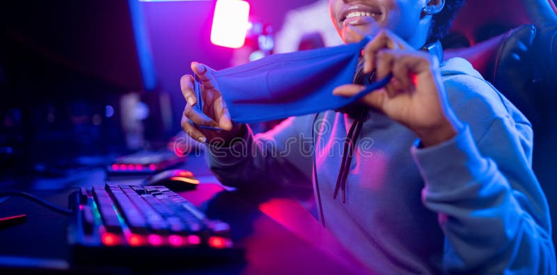 Donna d'azzardo africana con una maschera di sicurezza protegge il coronavirus e l'influenza gioca online con un computer fotografie stock