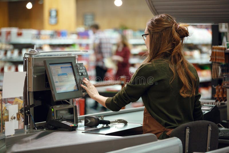 Back view photo of cashier women on workspace in supermarket shop. Looking aside. Back view photo of cashier women on workspace in supermarket shop. Looking aside.