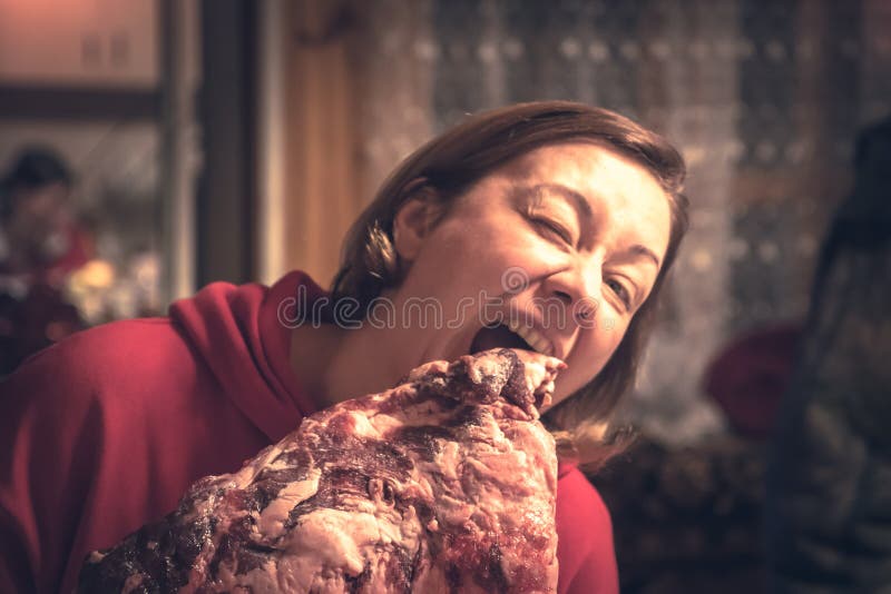 Donna del mangiatore della carne che tengono il grande pezzo della carne cruda e pronto da mangiare concetto non sano di cibo