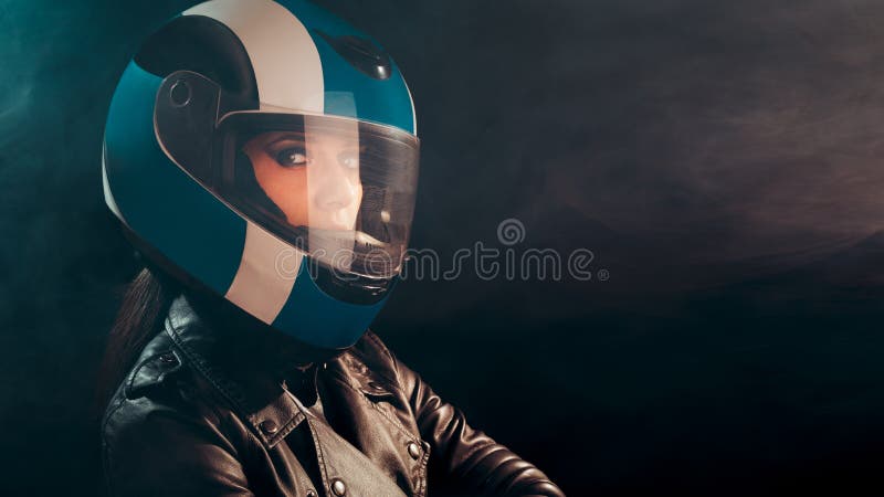 Donna del motociclista con il casco ed il ritratto di cuoio dell'attrezzatura