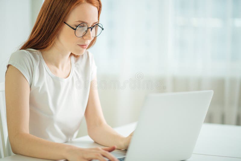 Donna della testarossa che per mezzo del computer portatile Lavorare femminile al computer portatile immagine stock Donna della testarossa che per mezzo del computer portatile Lavorare femminile al computer portatile immagine stock