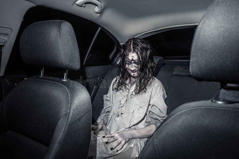 Donna dello zombie di orrore con il fronte sanguinoso nell'automobile fotografia stock Donna dello zombie di orrore con il fronte sanguinoso nell'automobile fotografia stock