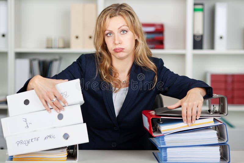 Donna di affari annoiata Behind Stacked Binders allo scrittorio fotografia stock Donna di affari annoiata Behind Stacked Binders allo scrittorio fotografia stock