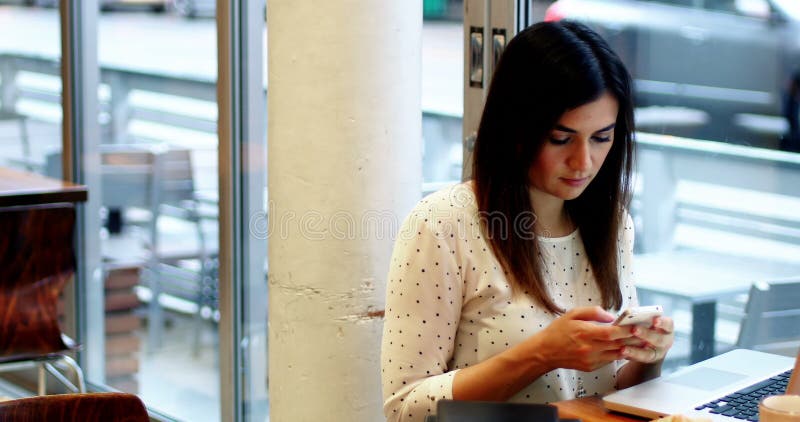 Donna di affari attenta che per mezzo del telefono cellulare