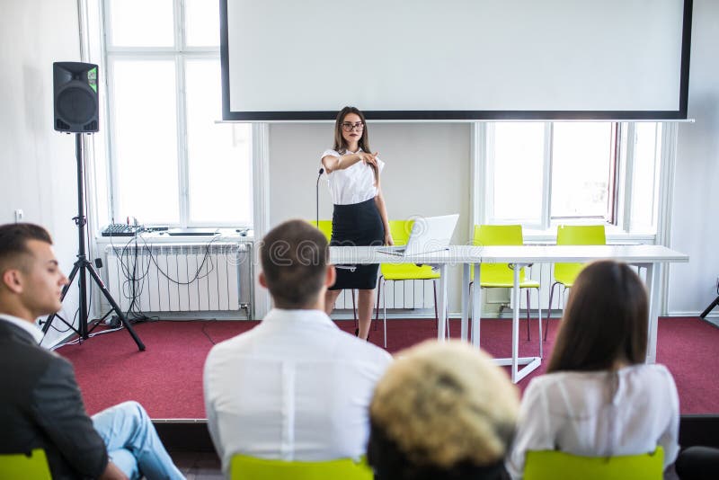 Donna di affari che risponde durante la riunione educativa del gruppo o l'addestramento corporativo con l'altoparlante o la vettu fotografia stock Donna di affari che risponde durante la riunione educativa del gruppo o l'addestramento corporativo con l'altoparlante o la vettu fotografia stock