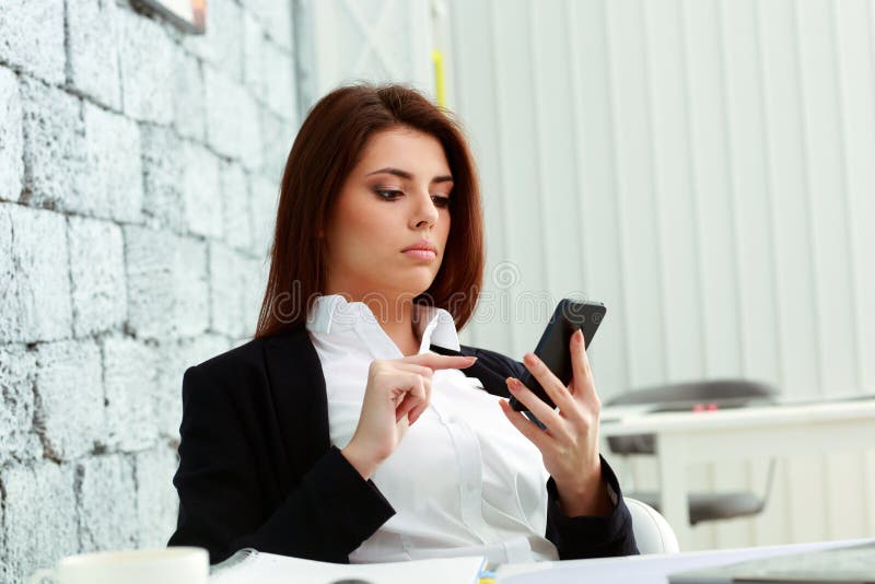 Donna di affari concentrata che esamina schermo dello smartphone immagini stock libere da diritti Donna di affari concentrata che esamina schermo dello smartphone immagini stock libere da diritti