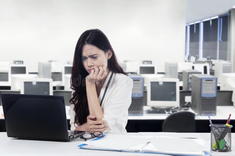 Donna di affari confusa che lavora con il computer portatile fotografie stock libere da diritti Donna di affari confusa che lavora con il computer portatile fotografie stock libere da diritti