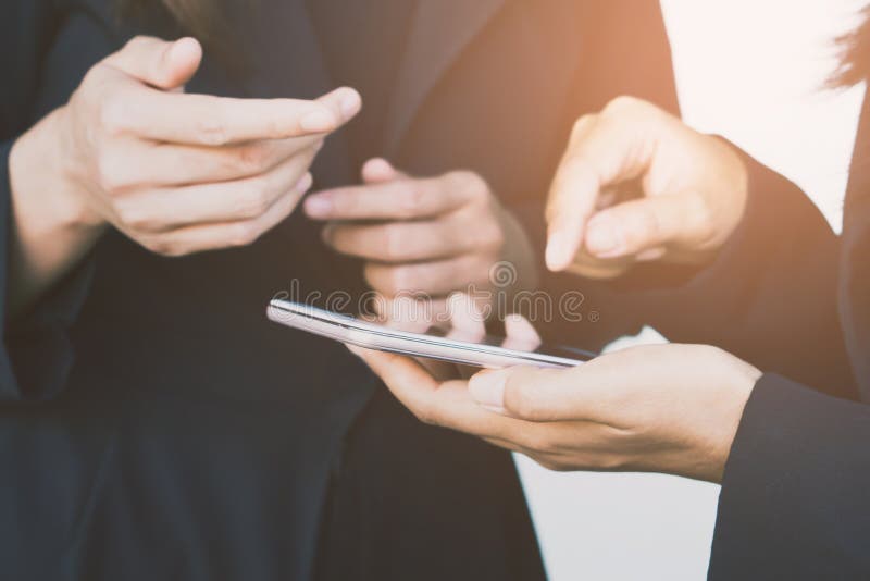 Donna di affari due che esamina telefono cellulare che parla del loro progetto immagini stock libere da diritti Donna di affari due che esamina telefono cellulare che parla del loro progetto immagini stock libere da diritti