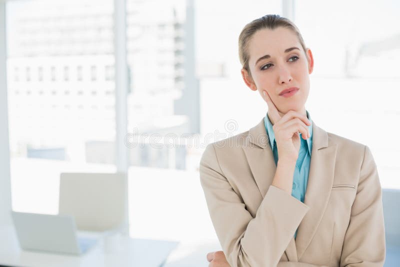 Donna di affari elegante premurosa sveglia che sta nel suo ufficio fotografia stock Donna di affari elegante premurosa sveglia che sta nel suo ufficio fotografia stock