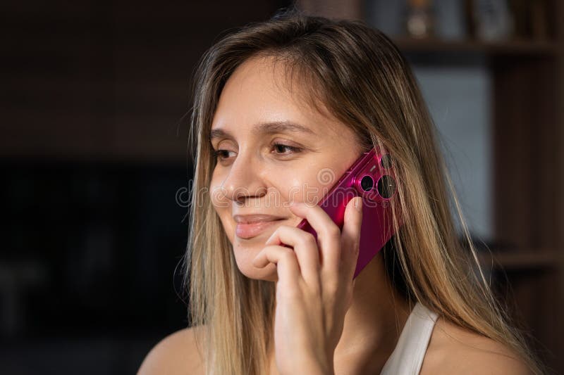Donna di aspetto europeo con un sorriso sul viso seduto su un divano che parla al telefono fotografia stock libera da diritti