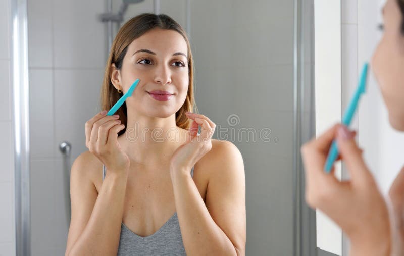 Depilazione facciale ragazza brasiliana che si rade il viso con il rasoio a  casa bella giovane donna che usa il rasoio sul bagno
