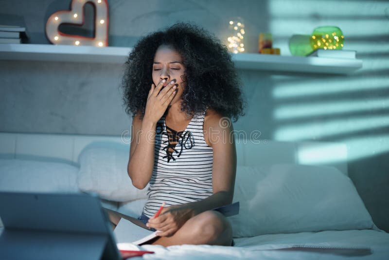 Donna di colore che studia alla notte con il computer portatile immagine stock Donna di colore che studia alla notte con il computer portatile immagine stock