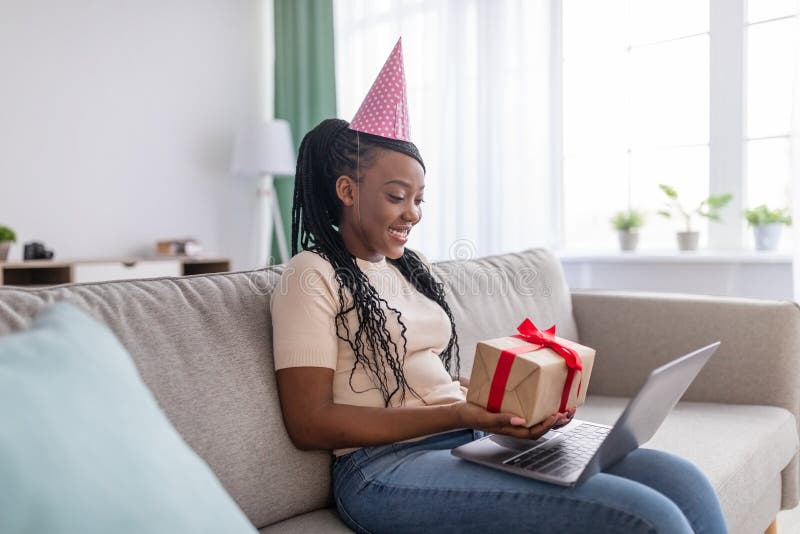 Donna di colore felice che fa festa online con il computer portatile fotografia stock