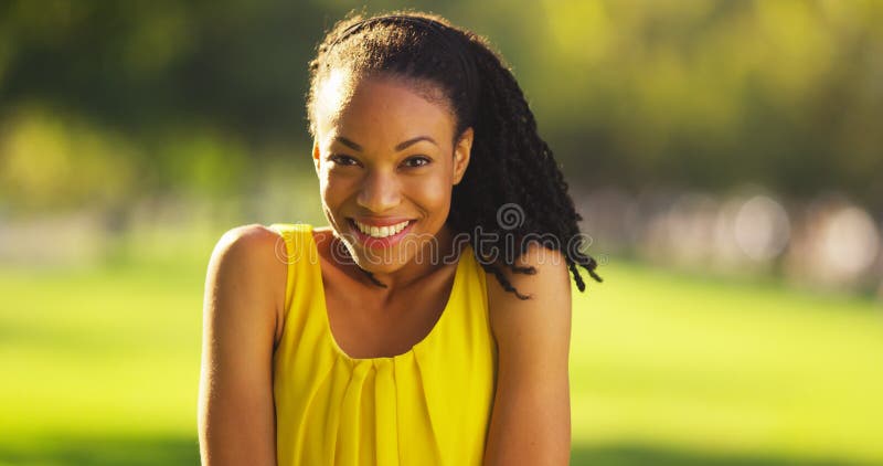 Donna di colore felice che sorride in un parco fotografia stock