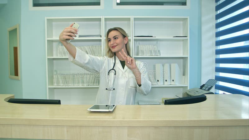 Donna di medicina sorridente che fa dei selfie con il telefono alla reception