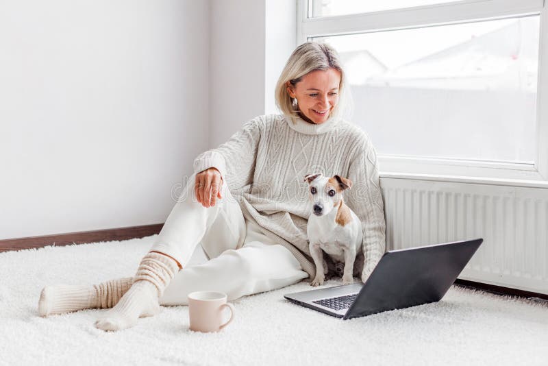 Donna di mezza età felice che usa il suo portatile a casa. Donna di mezza età felice che usa il suo computer portatile in una casa bianca accogliente