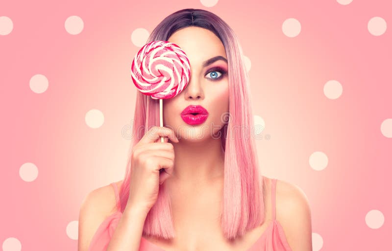 Donna di modello sexy di bellezza con l'acconciatura rosa d'avanguardia e la bella caramella della lecca-lecca della tenuta di tr