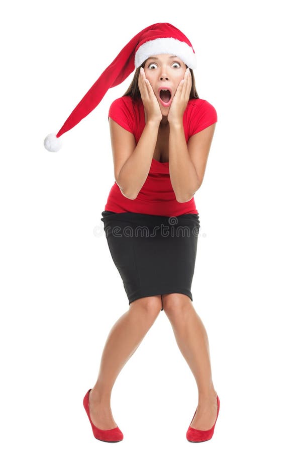 Christmas woman shocked. Woman with red santa hat shocked and surprised. Funny image of beautiful young Caucasian / Asian model isolated on white background in full length. Christmas woman shocked. Woman with red santa hat shocked and surprised. Funny image of beautiful young Caucasian / Asian model isolated on white background in full length.