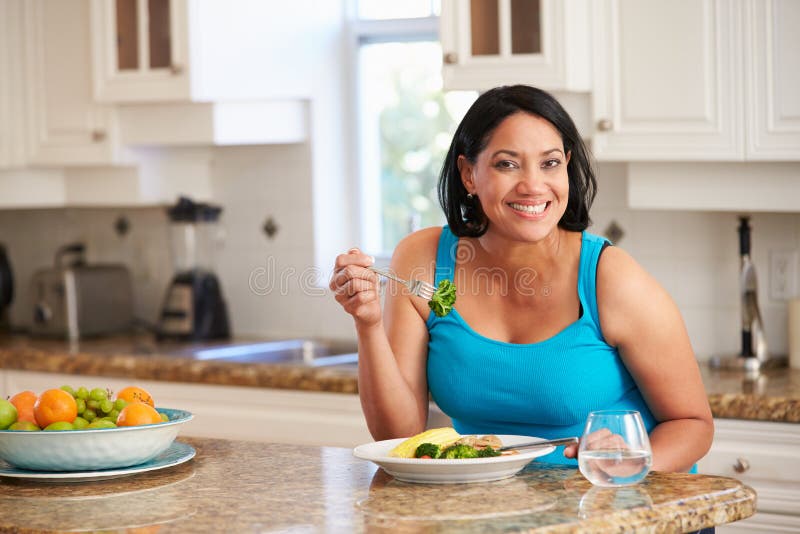 Donna di peso eccessivo che mangia pasto sano in cucina